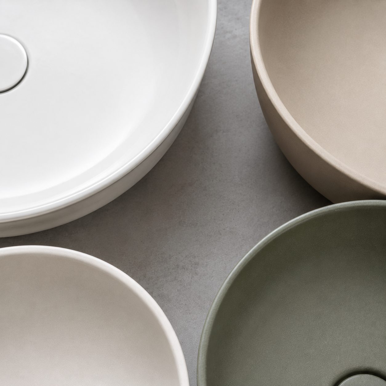 Close-up comparing glossy white, matte and coloured glaze finishes on ceramic wash basins showing the quality details that move price