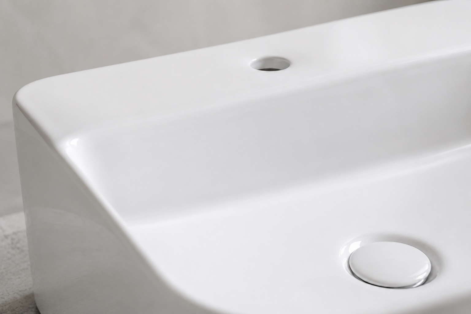 Close-up of a vitreous china basin rim and single tap hole showing glaze quality