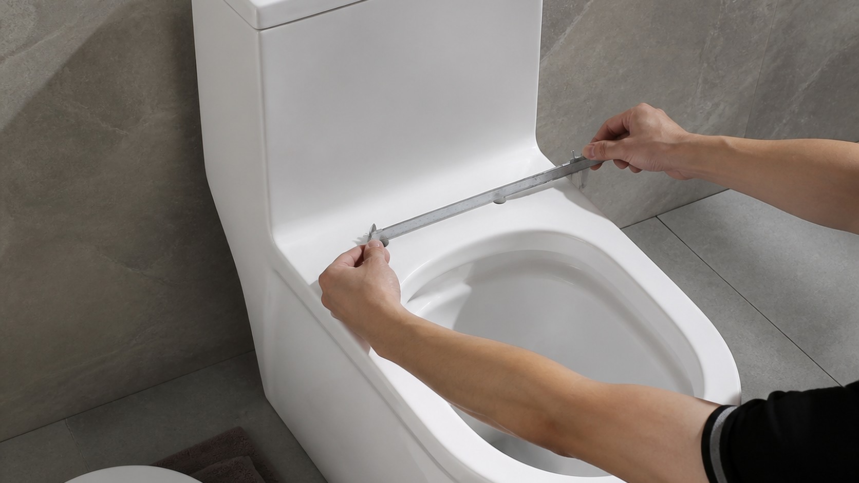 Technician measuring the two fixing points on a ceramic toilet before selecting a replacement seat