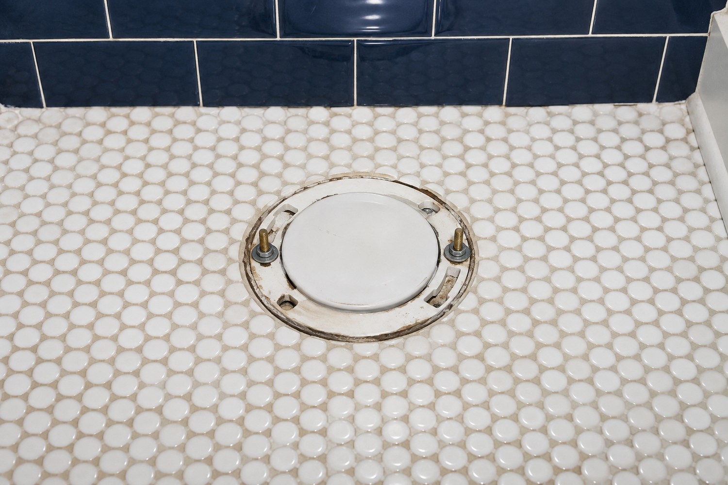 Exposed closet flange with temporarily capped waste opening before toilet installation