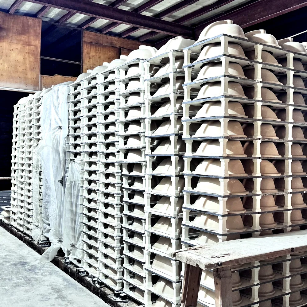 Greenware ceramic basins drying on racks